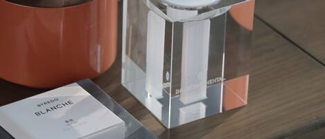 A clear glass bottle with a label, a white box with text, and a metallic container with a lid.