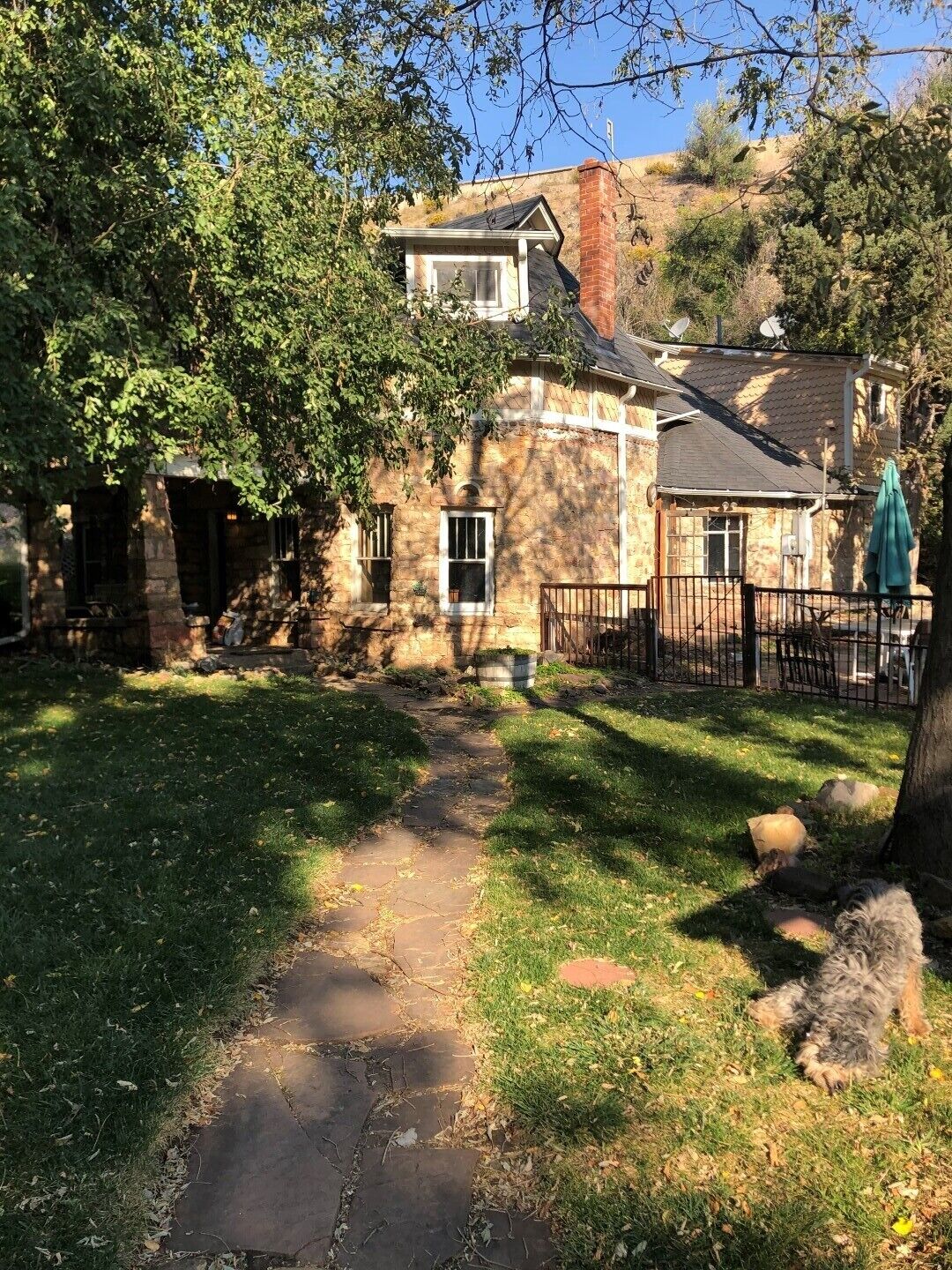 A stone house with a paved pathway leading to a gated entrance.