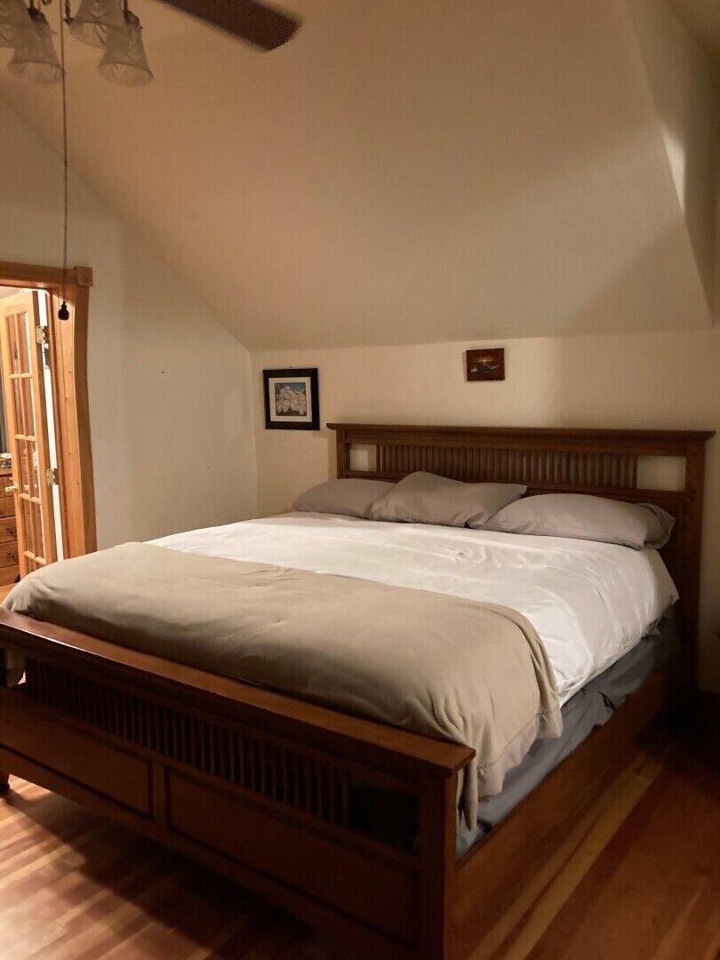 Quarto com cama de madeira, guarda-roupa de madeira e ventilador de teto.