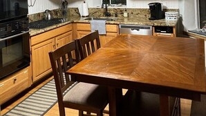 A kitchen with wooden cabinets, a granite countertop, a dining table, and a built-in oven. -  Mt. Vernon Ranch House near Red Rocks and Colorado Mountains, skiing. Est 1860 (Golden)