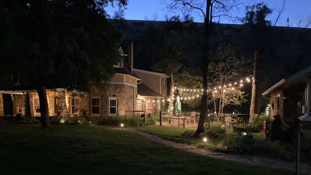 A stone house with a stone pathway leading to the entrance, surrounded by trees and a well-lit outdoor area with string lights. -  Mt. Vernon Ranch House near Red Rocks and Colorado Mountains, skiing. Est 1860 (Golden)