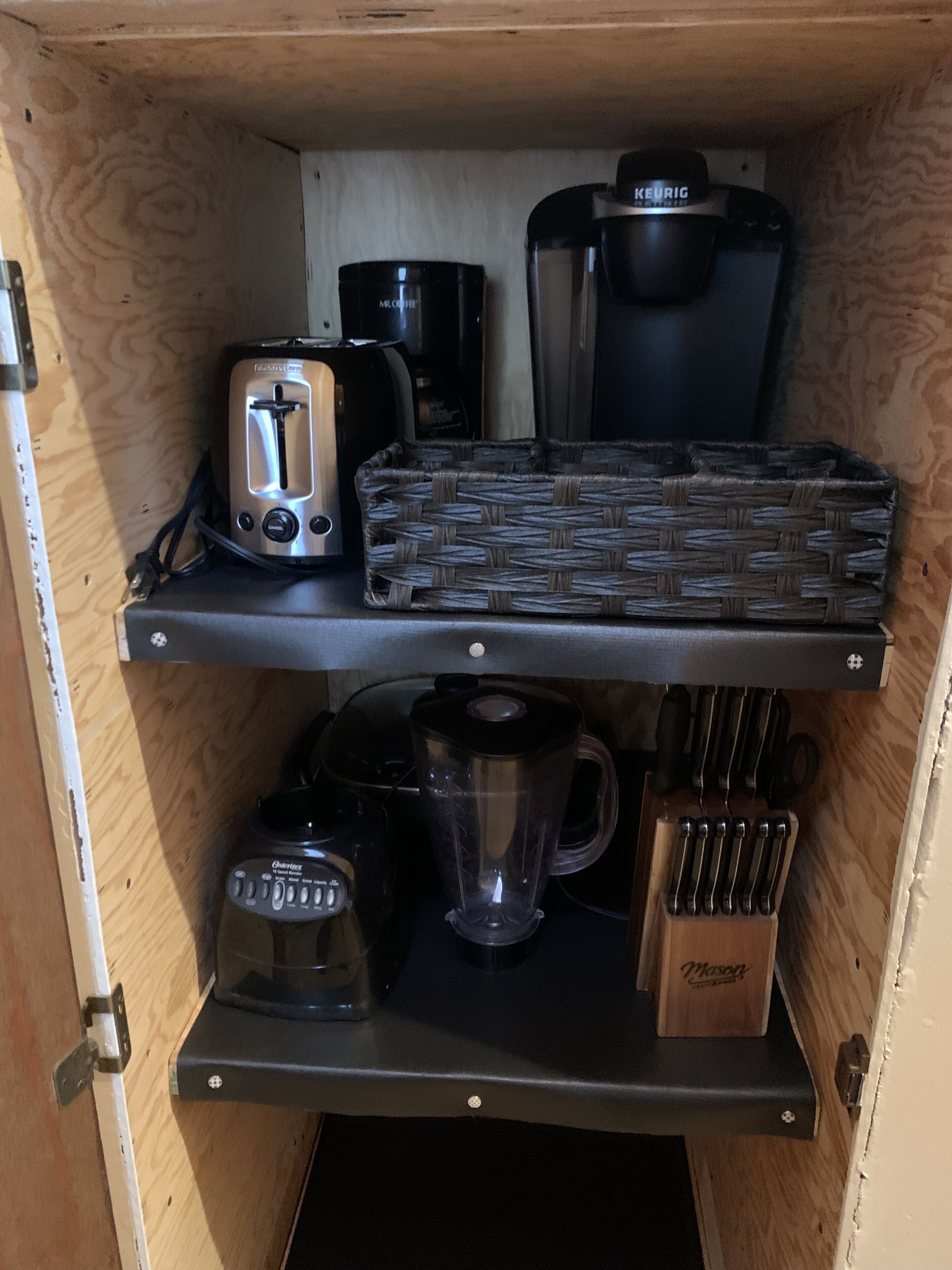 Een keuken met een broodrooster, koffiezetapparaat, blender en een messenblok op planken.