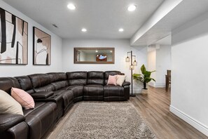 A modern living room with a sectional sofa, a large mirror, and a floor lamp.