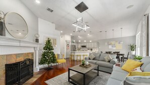 Un salon moderne avec une cheminée, une table basse, un canapé et un coin repas à l’arrière-plan.