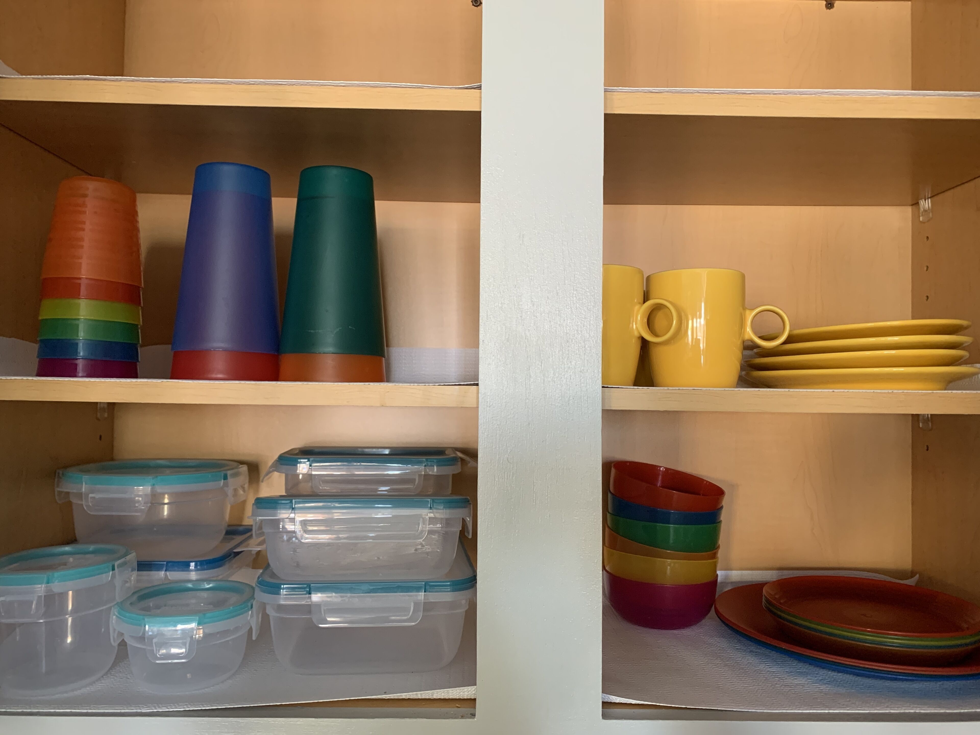 A storage unit with shelves containing plastic containers, colorful cups, and plates.