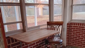 A corner seating area with a wooden table and two chairs, a brick wall, and large windows. - Family Friendly Fully Renovated Quiet House  (Dresden)