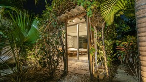 A private garden with a glass-enclosed bedroom, surrounded by lush vegetation and a stone pathway. - Villa el Oasis, luxurious Santa Marta getaway (rodadero)
