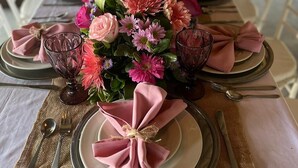 A long dining table with pink napkins tied with twine, a centerpiece of flowers, and silverware. - Villa el Oasis, luxurious Santa Marta getaway (rodadero)