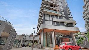 Um edifício de vários andares com design arquitetônico moderno, com varandas e grandes janelas.