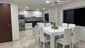Una cucina moderna con mobili bianchi, un tavolo da pranzo con sedie bianche e una ventola a soffitto.