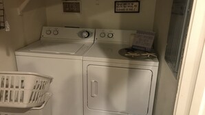 Une buanderie équipée d’un lave-linge, d’un sèche-linge et d’un panier à linge.