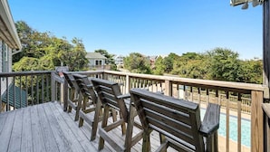 Eine Holzterrasse mit Bänken, die auf einen Swimmingpool blickt.