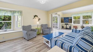 Ein geräumiges Wohnzimmer mit einem blau gestreiften Sofa, gemusterten Sesseln und einem Couchtisch.