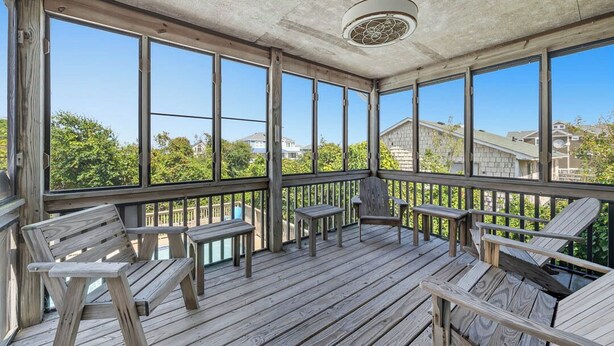 Eine überdachte Terrasse im Freien mit Holzmöbeln und großen Fenstern.