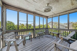 A covered outdoor deck with wooden furniture and large windows. - The Three Fish Inn | 1,110 ft. to the beach | Private Pool, Hot Tub (Duck)
