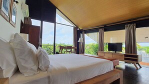 Een ruime slaapkamer met een groot bed, een bureau en een televisie.