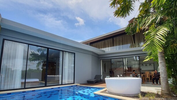 Een modern huis met een zwembad, grote schuifdeuren en een jacuzzi.