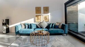 A modern living room with a teal sofa, a round coffee table, and wall art. - Mile Stone Villa (Jimbaran)