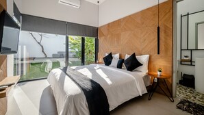 A modern bedroom with a large bed, a small side table with a plant, and a view of greenery through a sliding door. - Mile Stone Villa (Jimbaran)