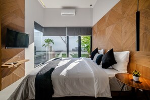 A modern bedroom with a large bed, a TV mounted on the wall, and a view of the outdoors.