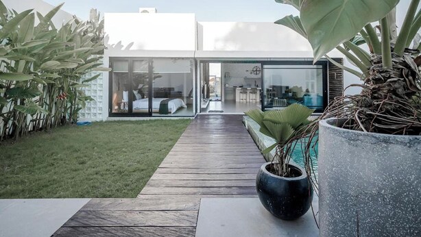 A modern house with a wooden deck leading to a glass door entrance. - Mile Stone Villa (Jimbaran)
