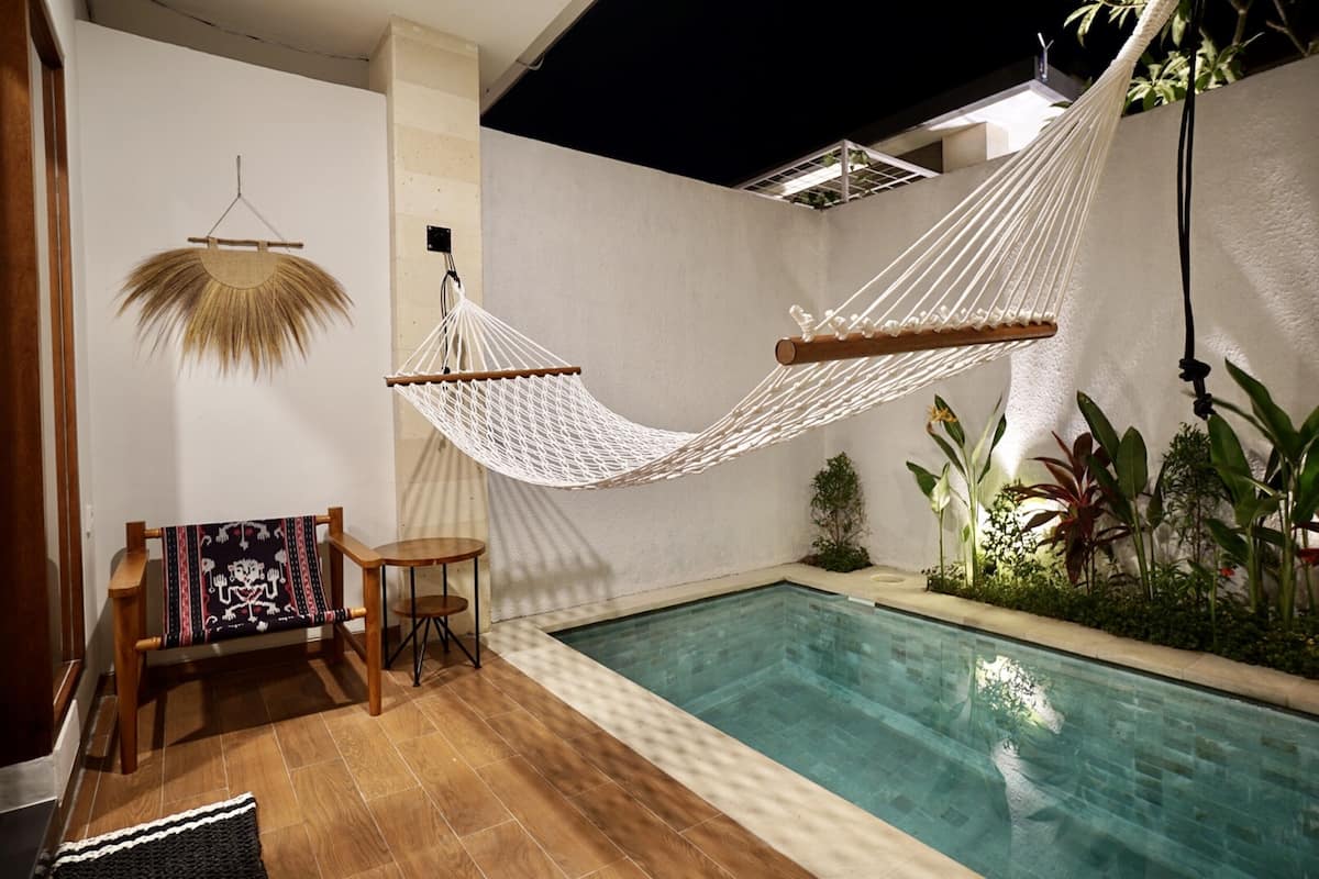 A pool area with a hammock, a small table, and a chair.