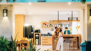A modern kitchen with a dining area, wooden furniture, and a bar counter. - The Kamare by Zuzu (Tibubeneng)