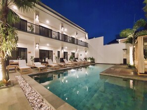 A hotel with a pool, lounge chairs, and a two-story building with balconies. - The Kamare by Zuzu (Tibubeneng)
