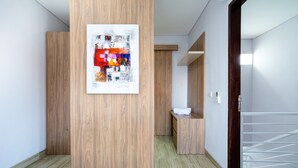 A modern hotel lobby with wooden paneling, a reception desk, and a colorful abstract artwork on the wall. - Little Nuts Villa (Jimbaran)