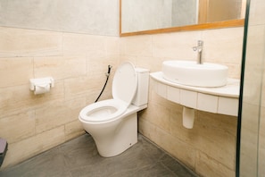 A modern bathroom with a toilet, sink, and mirror. - Natura Nusa Dua (Nusa Dua)