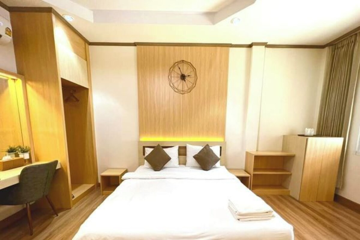 A hotel room with a bed, bedside tables, a desk, and a wardrobe.