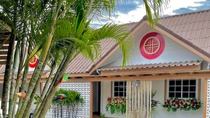 Um edifício com telhado em telhas, um emblema circular decorativo na fachada e uma entrada coberta.