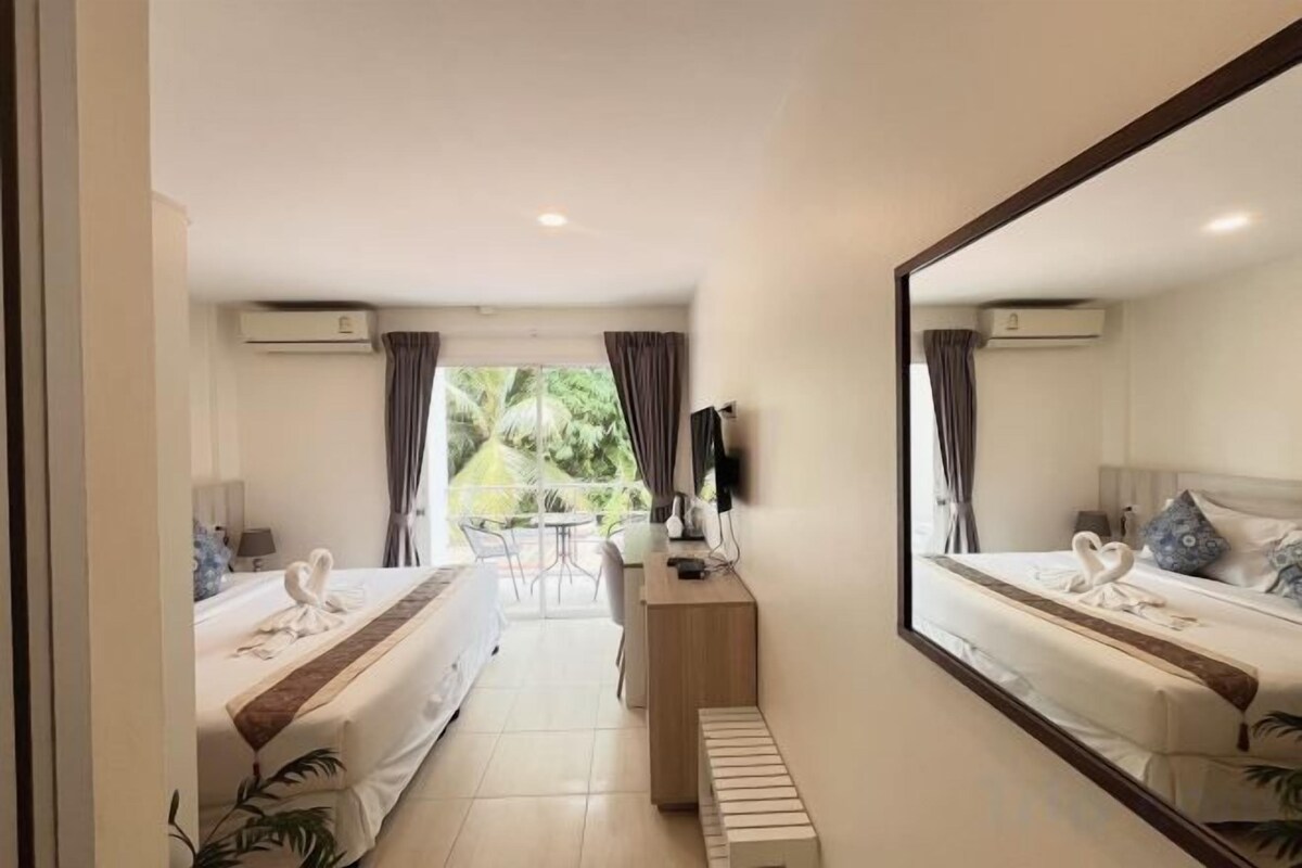 A hotel room with a bed, a desk, a chair, a TV, and a view of the outdoors.