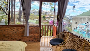 A room with a bed, a balcony with a view of the city, and a mural on the wall. - Books Home Dalat (Xuan Huong - Da Lat)
