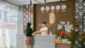 Un mostrador de recepción de hotel con un diseño moderno, que incluye una pared de paneles de madera, una barra de recepción y una pantalla de reloj.