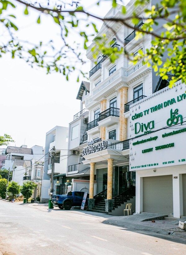 A hotel with a white facade, multiple balconies, and a sign advertising a luxury showroom. - Duong Chau Boutique Hotel (Tran Bien)