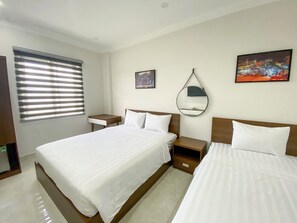 A hotel room with two beds, a bedside table, a nightstand, a window with blinds, a wall-mounted mirror, and two framed pictures. - Duong Chau Boutique Hotel (Tran Bien)