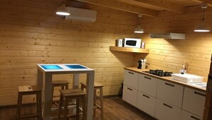 Una habitación con paneles de madera, una mesa y sillas, un microondas en un estante y un lavabo con armarios.