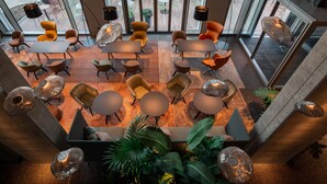 A modern indoor space with multiple seating areas, including tables and chairs, arranged in a spacious layout. - b'mine Frankfurt Airport, WorldHotels Crafted (Frankfurt)