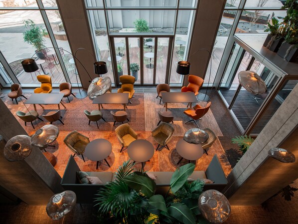 A modern indoor space with multiple seating areas, including tables and chairs, arranged in a spacious layout. - b'mine Frankfurt Airport, WorldHotels Crafted (Frankfurt)