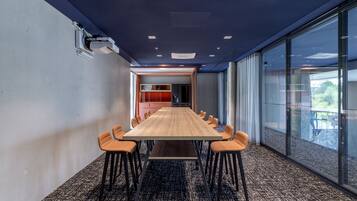 Un salón de conferencias con una larga mesa, varias sillas y una pared divisoria de vidrio.