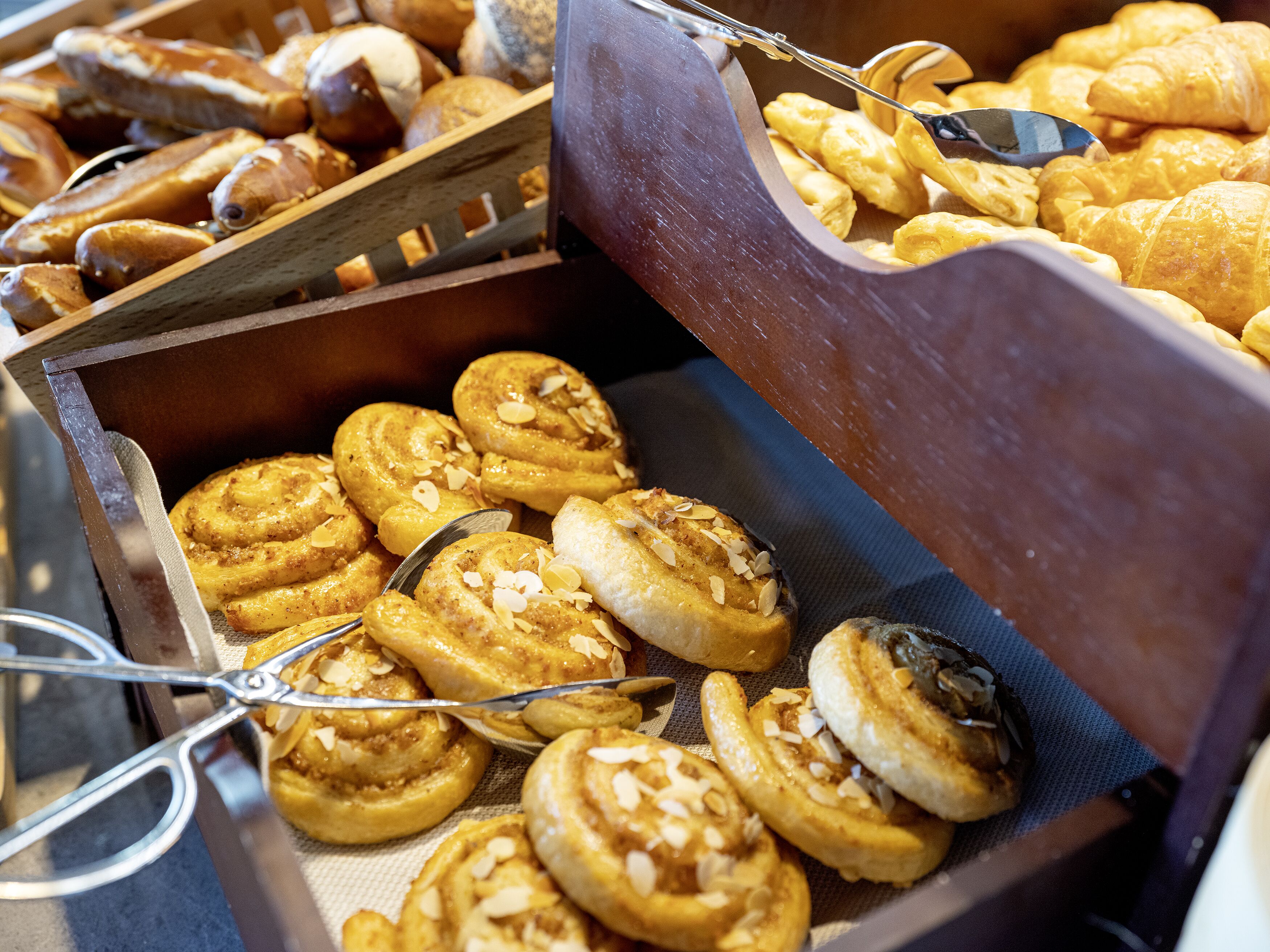 A variety of baked goods, including pastries and bread, displayed in a wooden basket.