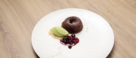 Un postre sobre un plato blanco, con una mesa de madera de fondo.