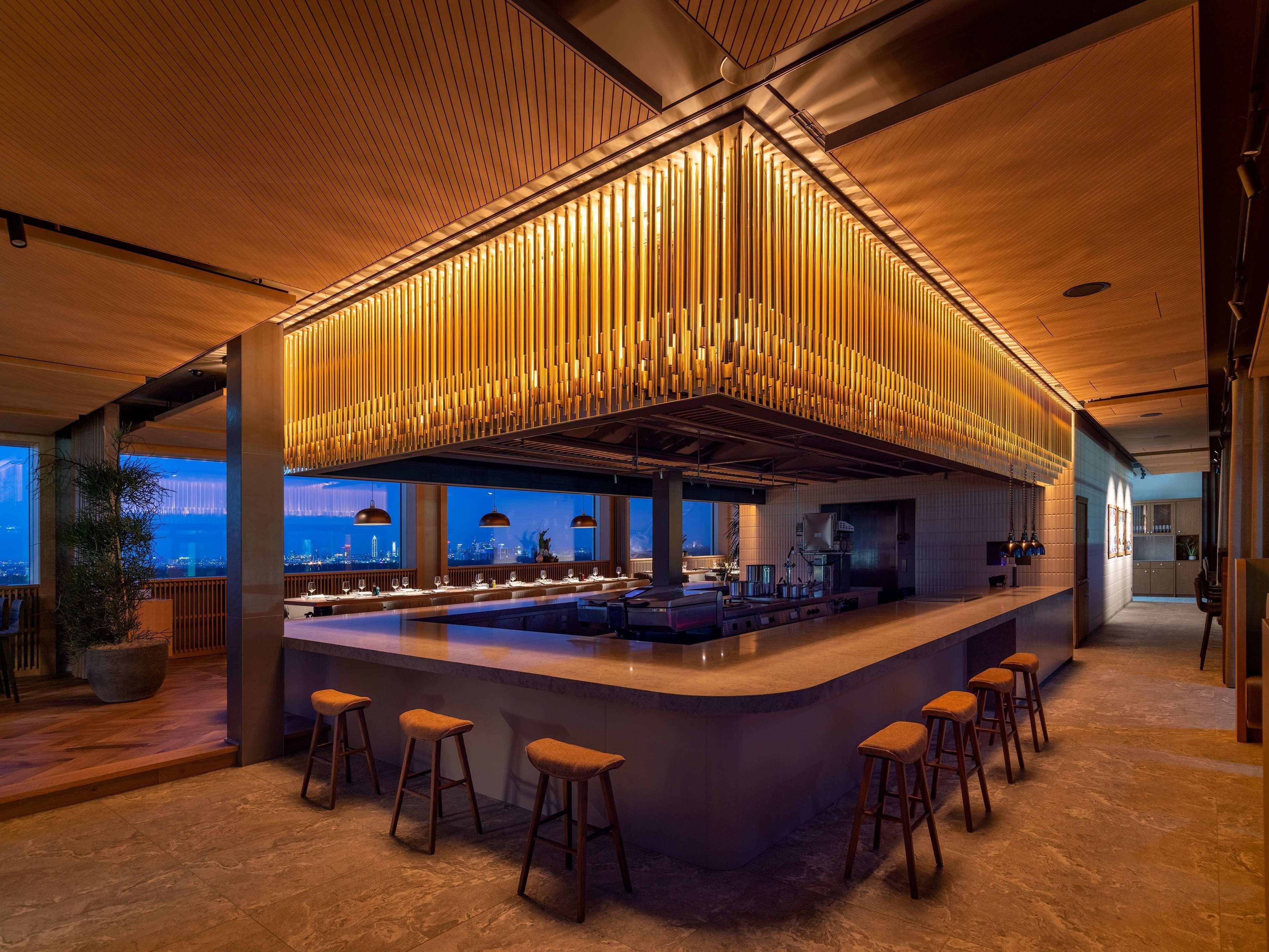 A modern bar area with a central island, bar stools, and pendant lighting.