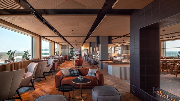 A spacious lounge area with a long table, comfortable seating, and a fireplace. - b'mine Frankfurt Airport, WorldHotels Crafted (Frankfurt)