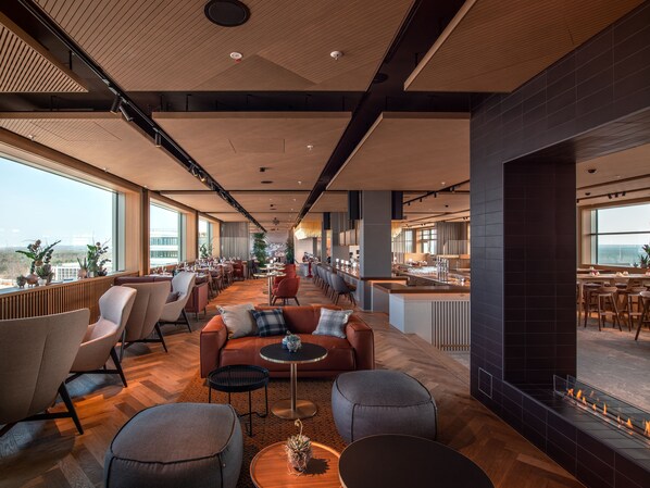 A spacious lounge area with a long table, comfortable seating, and a fireplace. - b'mine Frankfurt Airport, WorldHotels Crafted (Frankfurt)