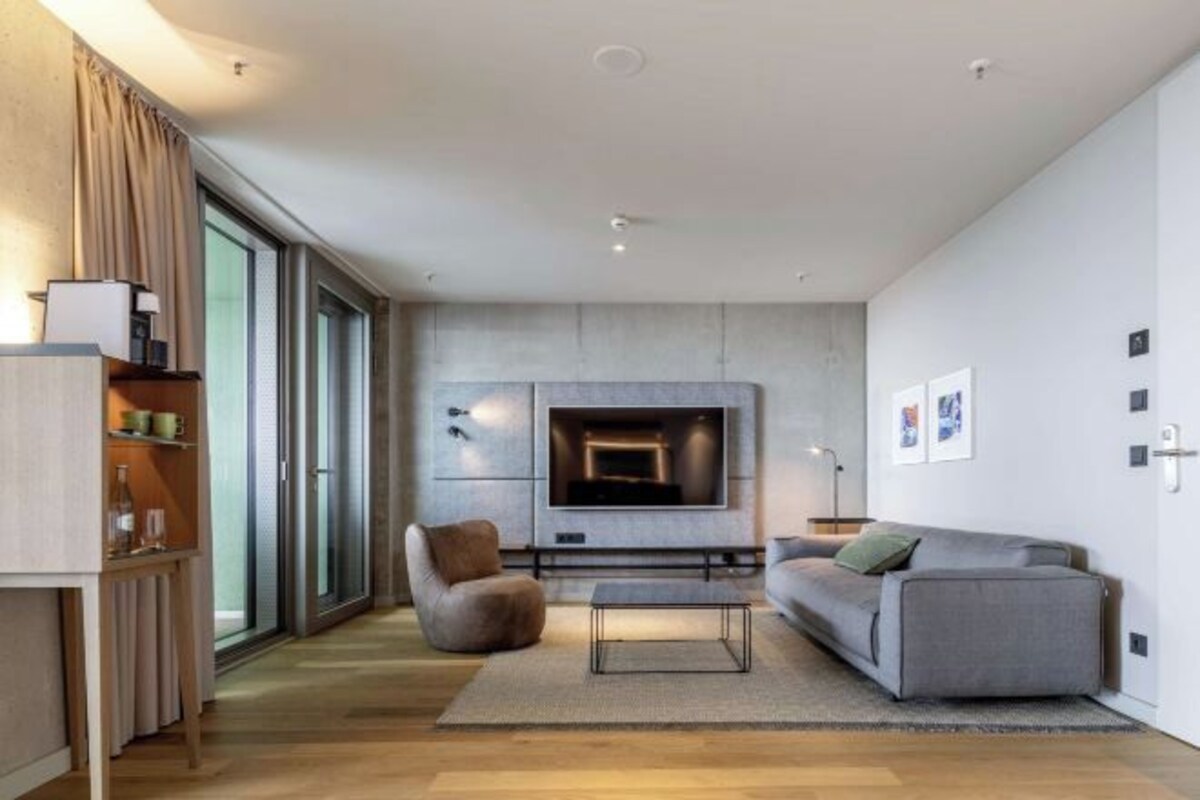 A modern living room with a fireplace, a sofa, a coffee table, and a television.