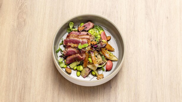 A bowl of food with various vegetables and meat on a wooden surface. - b'mine Frankfurt Airport, WorldHotels Crafted (Frankfurt)