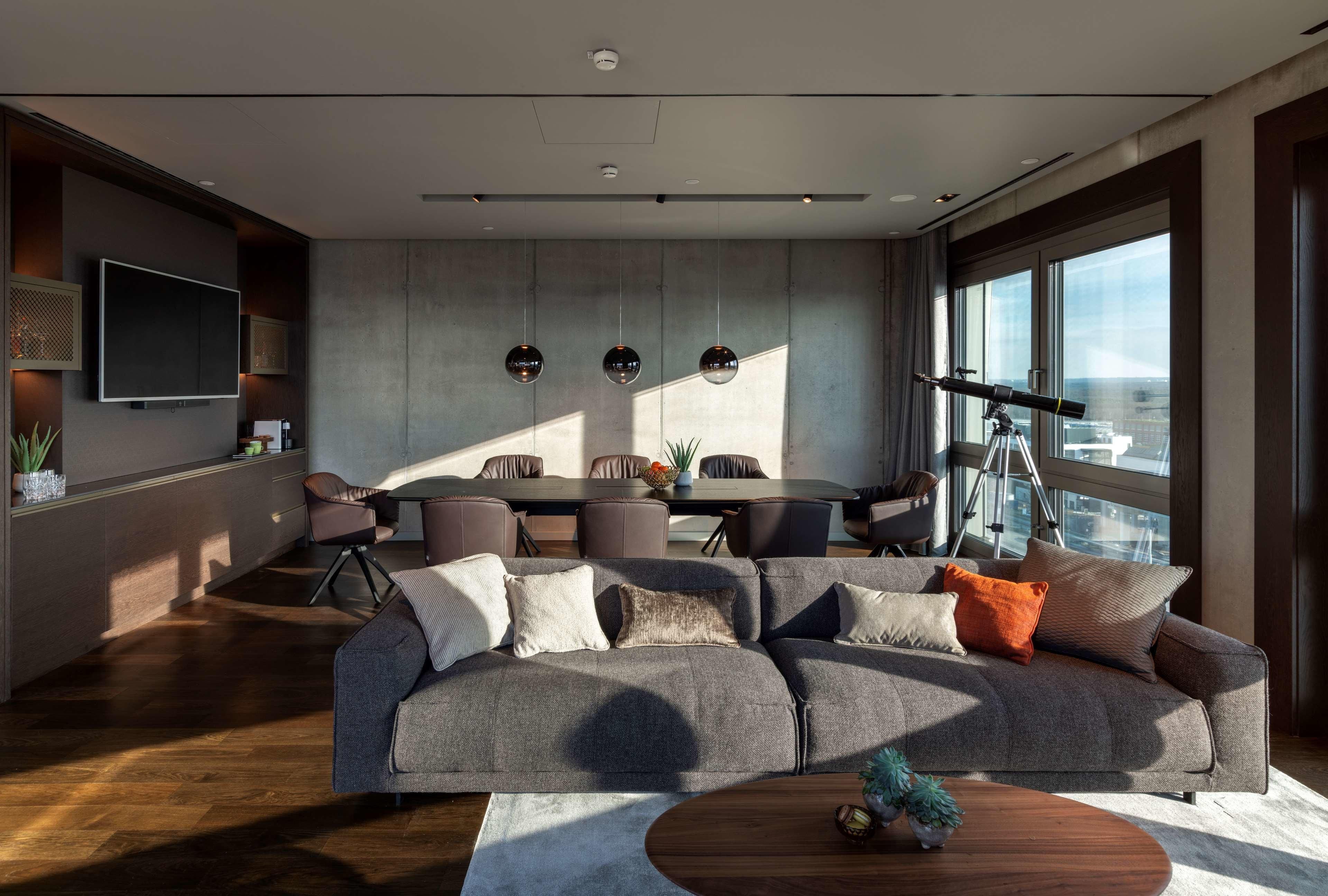 A modern living room with a large sofa, a dining table, and a telescope.