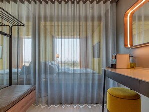 A modern hotel room with a bed, a desk, a chair, and a large window with sheer curtains. - b'mine Frankfurt Airport, WorldHotels Crafted (Frankfurt)